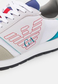 Sneaker da uomo con tomaia in rete bianca e dettagli in suede grigio, ricami rossi e particolari blu. Suola in gomma per una migliore aderenza.