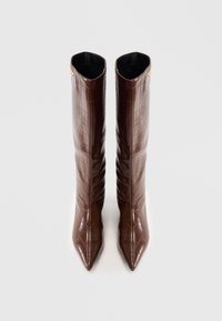 Bottes marron en faux cuir crocodile, hauteur genou, avec un bout pointu et une texture lisse, ornées d'un accent doré en haut.