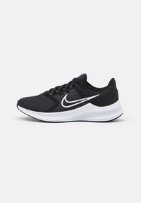 Zapatilla deportiva negra con parte superior de malla transpirable, acentos blancos, collar acolchado, suela amortiguadora y suela de goma texturizada.
