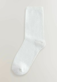 White cotton sock, mid-calf length, featuring a textured knit pattern and reinforced toe. Elastic cuff at the top for snug fit.