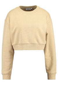 Zkrácená mikina ve světle béžové barvě, vyrobená z měkké látky. Má dlouhé rukávy a žebrovaný výstřih. Jednoduchý design, bez dalších vzorů.