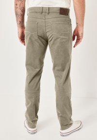 Beige corduroy pants with a straight cut, featuring back pockets and a leather patch at the waistband. Smooth texture, subtle stitching details.