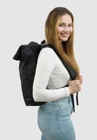 Zwarte roll-top rugzak gemaakt van duurzaam materiaal. Kenmerkt zich door verstelbare banden, een gestroomlijnde vorm en een minimalistisch ontwerp.
