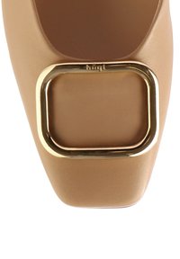 Beige čtvercové boty s hladkým koženým povrchem a velkým zlatým obdélníkovým přezkovým akcentem vpředu.
