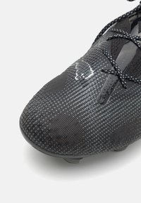 Scarpa da calcio nera con tomaia testurizzata a motivo esagonale, con tacco nero liscio e lacci a contrasto.