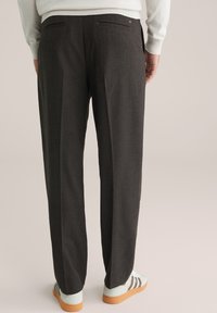 Sötétszürke, egyenes szabású, szabott nadrág, két hátsó zsebbel és sima textúrával, világos sportcipővel párosítva.