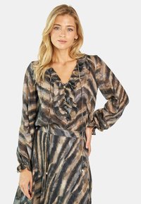 Blusa de estampado marrón y gris con cuello con volantes, acentos de botones y mangas largas. Tejido ligero con una textura suave y fluida.