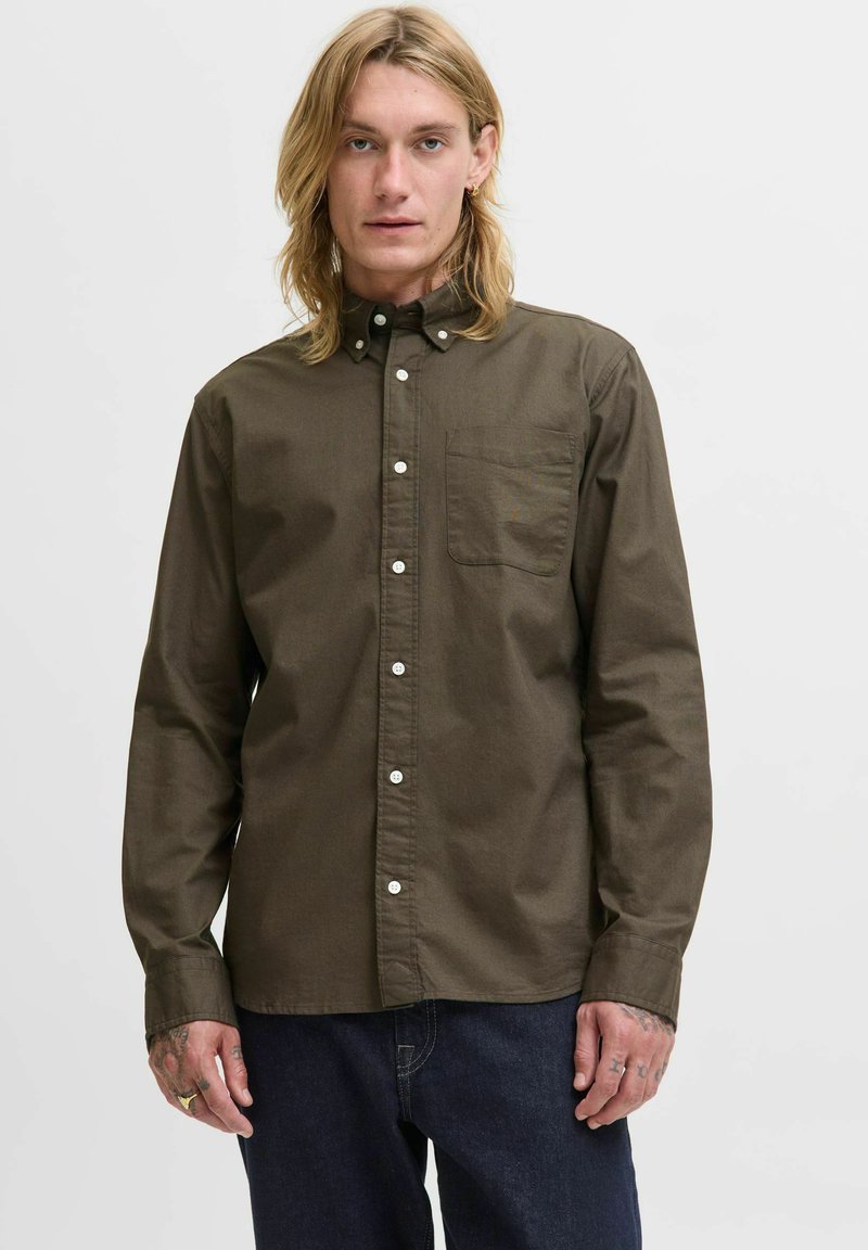 Bruin langemouwen shirt met een button-down kraag, een borstzak, witte knopen en een zachte textuur. Gemaakt met donkerblauwe spijkerbroek.