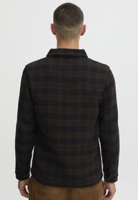 Men's flannel shirt in dark blue and brown plaid. Soft textured fabric, collared with long sleeves, and buttoned cuffs.
