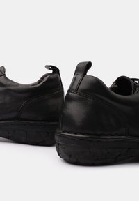 Black leather shoes with rubber soles, rounded shape, slight texture, and rear pull tabs for easy wear.