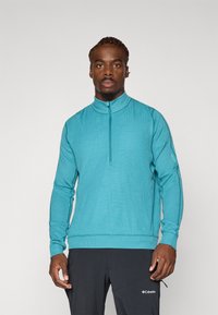 Hele sinine, pikkade varrukatega pullover, millel on pool-kleidiga krae ja tekstureeritud kangas. Kombineeritud tumedate pükstega, esitledes kontrastset välimust.