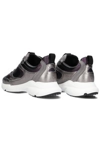 Metallische zilveren sneakers met zwarte accenten en gestructureerde detailing. Chunky witte zool met een getextureerde zwarte onderkant, voorzien van elastische enkelsteun.