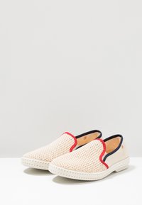 Instap schoenen met een geweven beige bovenwerk, rode en marineblauwe accenten op de randen en een gestructureerde witte zool. Rond neusontwerp.