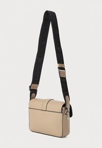 Bežinė odinė per petį nešama rankinė su struktūrizuotu dizainu, su užsegamu dangteliu ir juodu dirželiu, ant kurio yra įspaustas "Michael Kors".