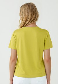 T-shirt manica corta di un brillante verde lime, realizzata in tessuto morbido, con collo rotondo e vestibilità rilassata.