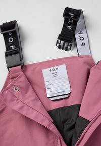 Roze jasseninterieur met zwarte voering, voorzien van verstelbare zwarte bandjes en een verzorgingslabel voor namen en maat 116 (5-6 jaar).