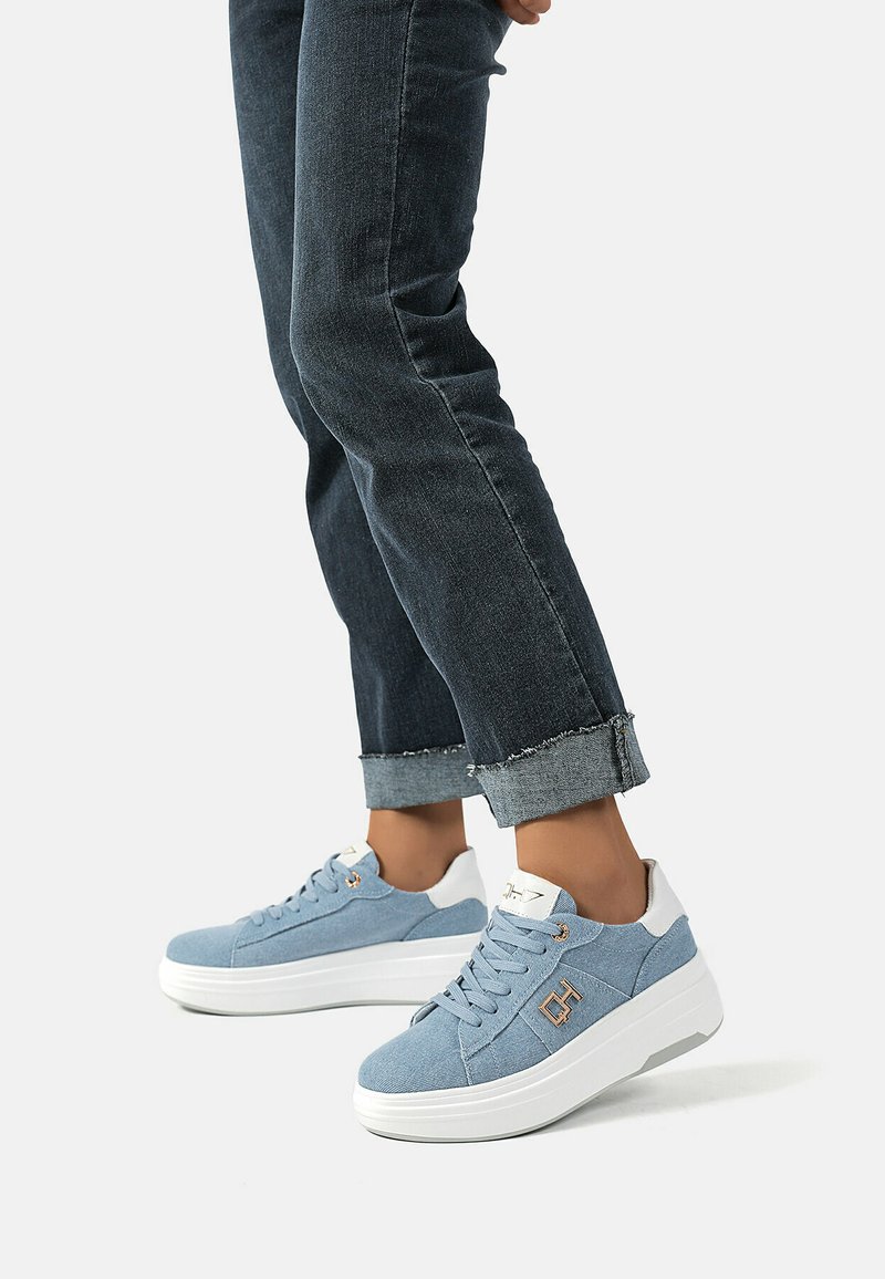 Sneaker in tela azzurro chiaro con suola in gomma bianca, dotate di dettagli in oro, punta rotonda e superficie testurizzata simile al denim.