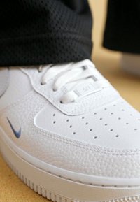 Vita läder sneakers med en texturerad finish, perforerad tåbox och grå accenter. Har platta vita skosnören och räfflad gummisula.