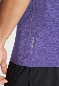Fioletowa sportowa koszulka dzianinowa z teksturowanym materiałem i odblaskowym napisem "PERFORMANCE KNIT" z boku, zestawiona z czarnymi szortami.