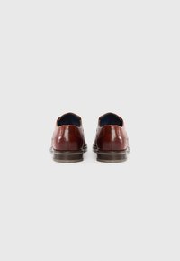 Chaussures en cuir marron avec une texture lisse, une forme arrondie et un détail de talon contrastant. L'intérieur est doté d'une doublure bleue.