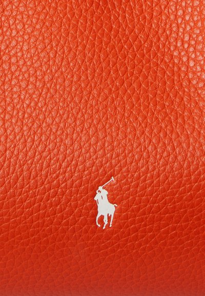 Oranžna teksturirana površina iz usnja z belim logotipom polo igralca in konja v spodnjem desnem kotu.