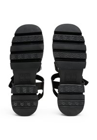 Svart sandaler med teksturerte gummisåler, som har justerbare stropper og et solid design. Sålene har et sikksakk-mønster for bedre grep.