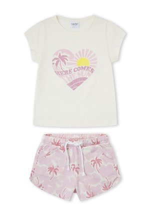 Camisa crema de manga corta con corazón rosa, gráfico de palmera y sol y texto "Here comes the sun", combinada con shorts rosa con estampado de palmeras.