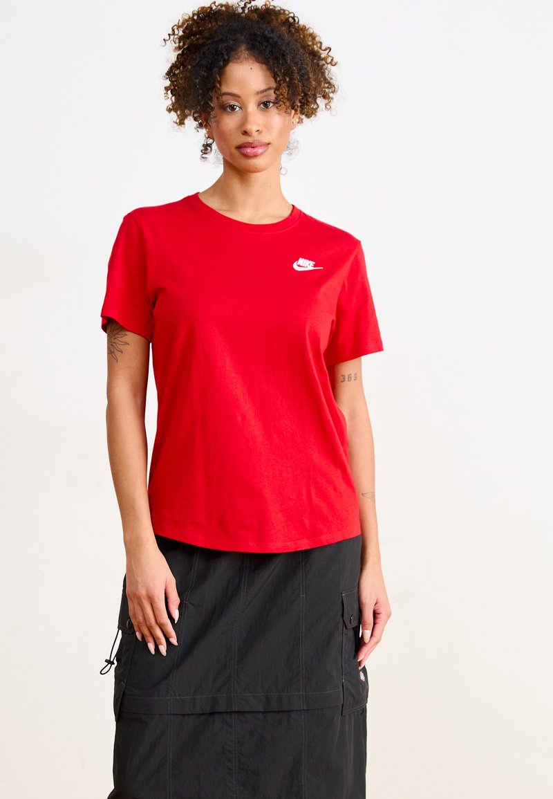 Tricou din bumbac roșu cu guler rotund și mâneci scurte. Dispune de un logo alb Nike pe pieptul stâng. Asortat cu o fustă neagră.