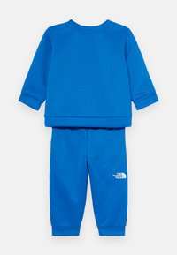 Βασιλικό μπλε φόρμα από μαλακό ύφασμα. Διαθέτει μπλούζα με μακριά μανίκια και παντελόνι με ταιριαστά μανίκια με ραφές. Λογότυπο στο αριστερό πόδι.