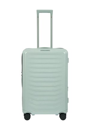 Valise rigide avec un extérieur texturé vert menthe, deux roues lisses, une poignée extensible et un compartiment zippé.