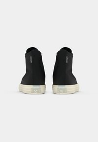 Sneakers nere alte in materiale di tela texturizzata, con suole in gomma bianca a contrasto e dettaglio del logo ricamato sul lato.
