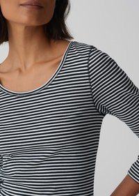 Langärmliges Oberteil mit schwarz-weißem Streifenmuster, Rundhalsausschnitt und sichtbaren Nähten, gefertigt aus einem weichen, leichten Stoff.