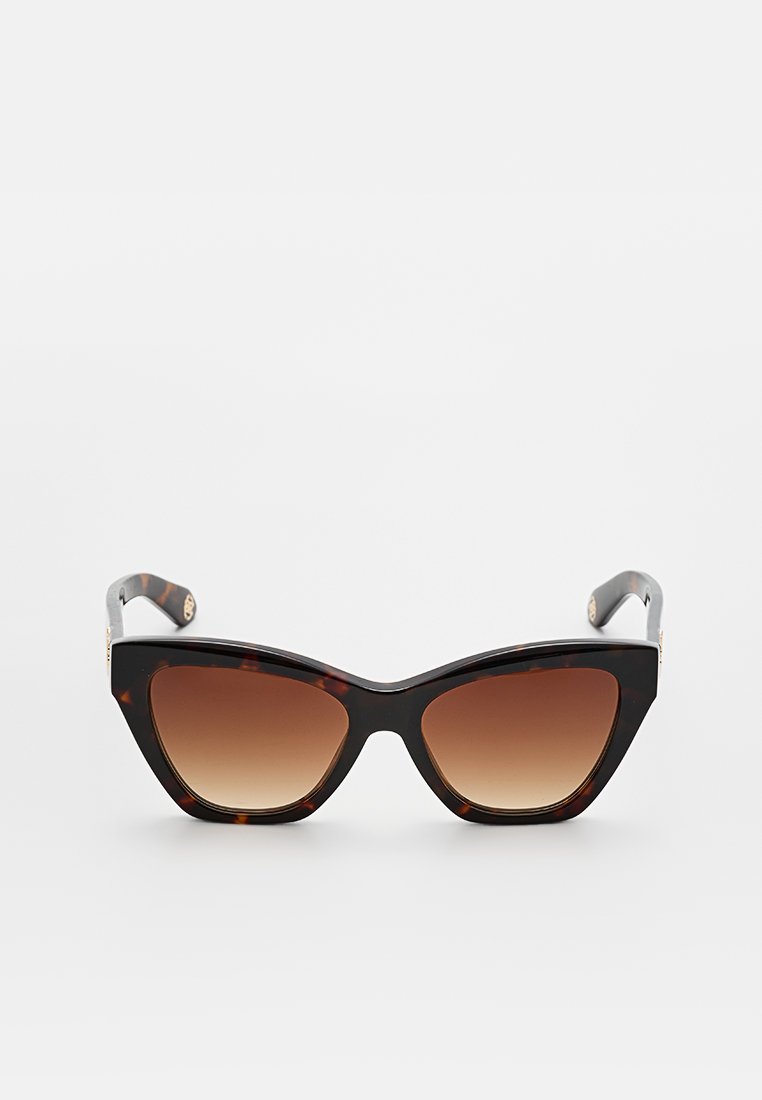 Lunettes de soleil en forme d'œil de chat avec une monture en écaille de tortue, des verres bruns dégradés et des branches noires brillantes avec des accents dorés.