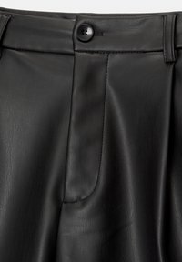 Pantalon noir en similicuir en gros plan montrant un bouton, une passants de ceinture et des détails de poche avant avec une texture lisse et des coutures discrètes.
