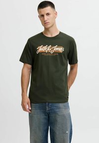 Olijfgroene T-shirt van katoen met korte mouwen, voorzien van een wit en oranje grafisch logo op de voorkant en een ronde hals.