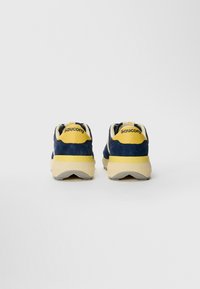 Sneaker in suede blu navy con dettagli gialli e suola in gomma. Presentano un colletto e una linguetta sul tallone imbottiti con il nome del marchio sul retro.