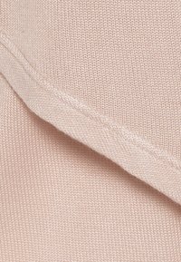 Soft pink knitted fabric featuring a smooth texture, with a folded edge showing a fine, subtle stitch detail along the hem.