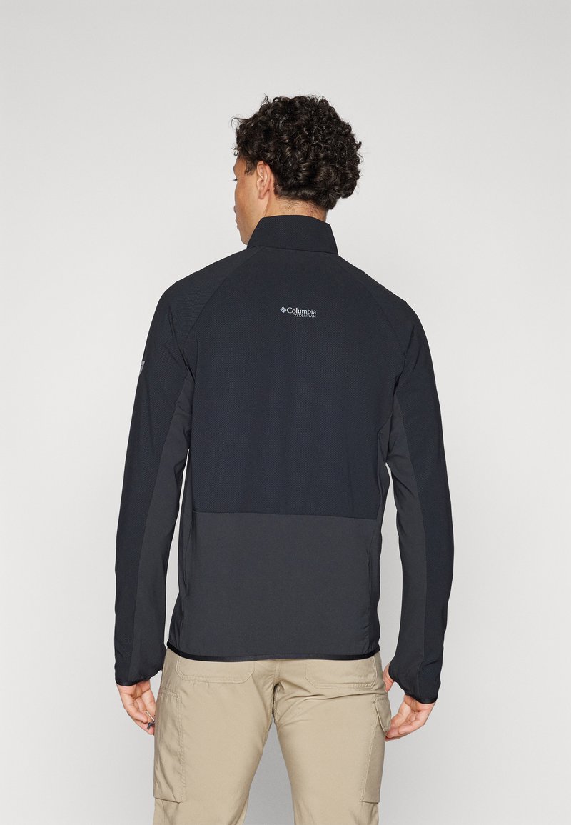 Schwarze Jacke mit glatter Textur und hohem Kragen, ausgestattet mit einem Oberteil im Netzmuster. Enthält ein Logo auf der Rückseite.