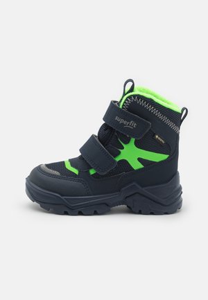 Bottines bleu noir avec des accents vert fluo, fabriquées en textile et matériaux synthétiques, comportant deux sangles Velcro et une semelle robuste.