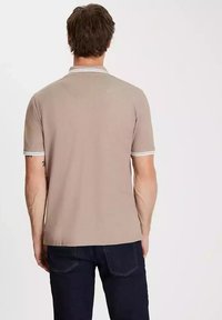 Beżowa koszulka polo z krótkim rękawem z białymi paskami przy kołnierzu i mankietach. Gładka tekstura, klasyczny krój i nowoczesne dopasowanie.