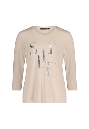 Beżowa koszula z długim rękawem z metalicznym srebrnym napisem "STYLE" ozdobionym ćwiekami. Gładka tekstura i luźny fason.