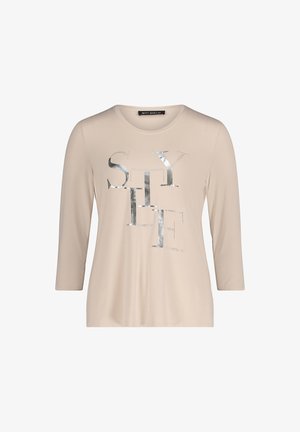 Beige shirt met lange mouwen, voorzien van een zilverkleurige metalen "STYLE" opdruk met studs. Soepele textuur en een comfortabele, losse pasvorm.