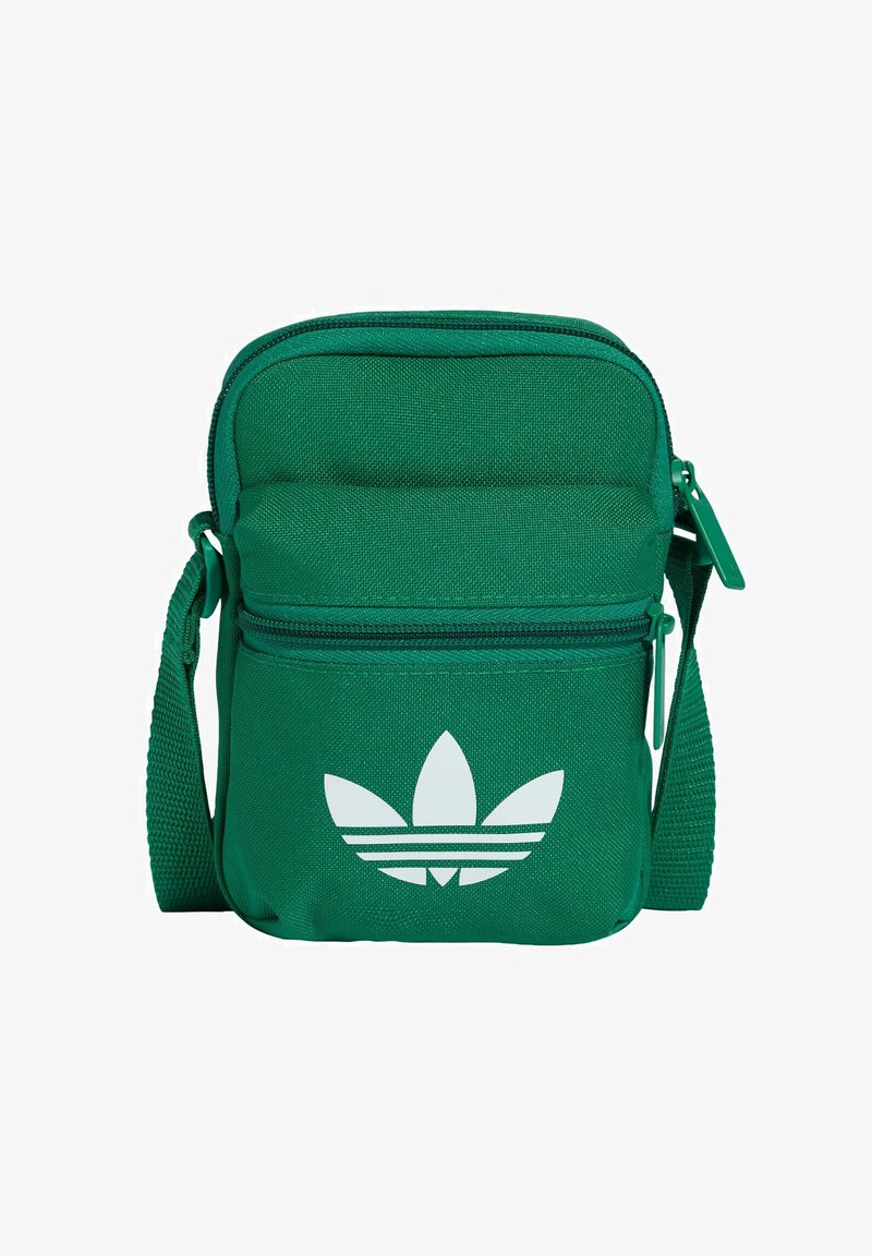 Zielona torba na ramię z tkaniny z zamkiem błyskawicznym, wyściełaną przednią częścią, regulowanym paskiem i białym logo Adidas Trefoil na przodzie.