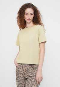 Ανοιχτό κίτρινο, κοντομάνικο μπλουζάκι με στρογγυλή λαιμόκοψη, άνετη εφαρμογή και απαλή υφή, συνδυασμένο με τζιν με μοτίβο λεοπάρ.