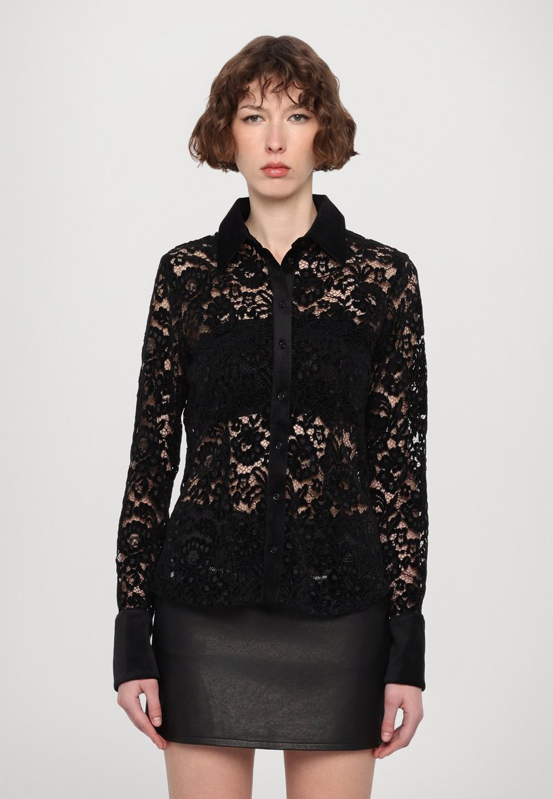 Svart bluse i blondestoff med krage og knappelukking. Lange ermer med svarte mansjetter, med blomsterdesign og semi-transparent tekstur.