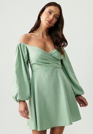 Green off-the-shoulder dress with a fitted bodice, balloon sleeves, and a flowing skirt. Made from a soft, textured fabric.