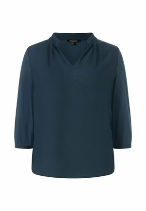 Dunkelbluse aus glattem Stoff, mit V-Ausschnitt, leichten Falten an den Schultern und dreiviertellangen Ärmeln.