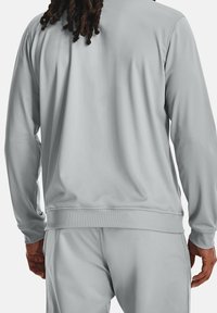 Grå sporttröja med slät textur, ribbade muddar och midjeband, med en avslappnad passform och minimalistisk design.