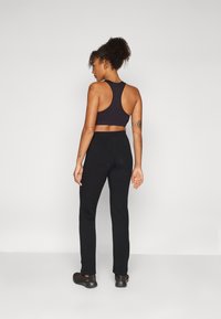 Black athletic crop top with racerback design, paired with fitted black pants, both made of stretchy fabric. Worn with dark athletic shoes.