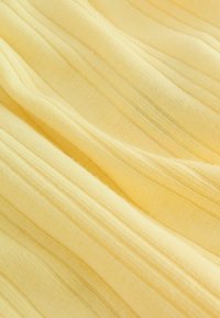 Weicher, gelber Rippstoff mit vertikalen, strukturierten Linien und sanften Falten.